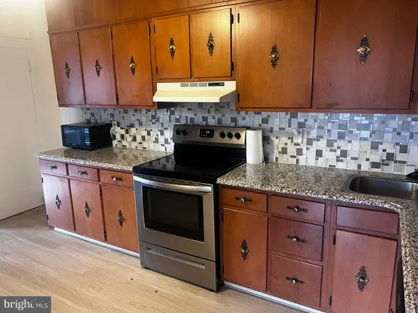 a kitchen with granite countertop a sink cabinets and stainless steel appliances