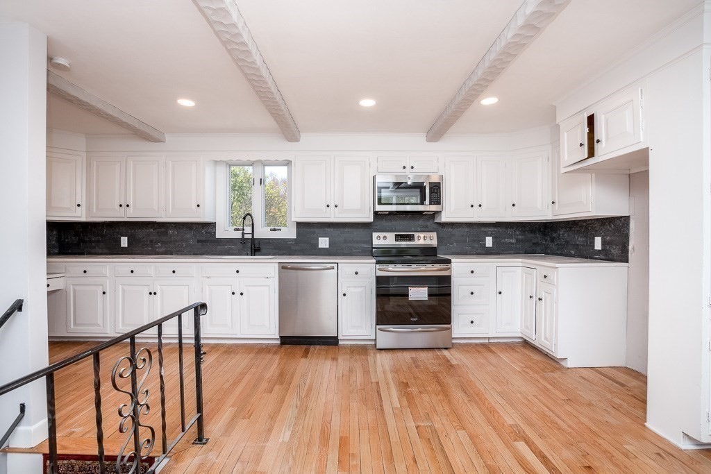 570 Canton Street Stoughton, MA 02072 - Photo 9 of 41 a kitchen with stainless steel appliances a stove top oven a sink and white cabinets with wooden floor
