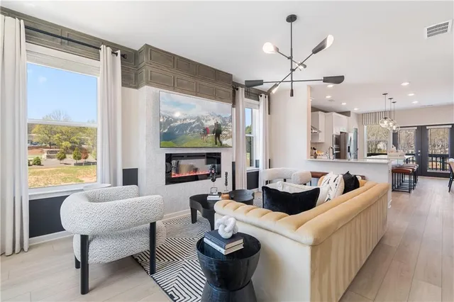 a living room with furniture kitchen view and a chandelier