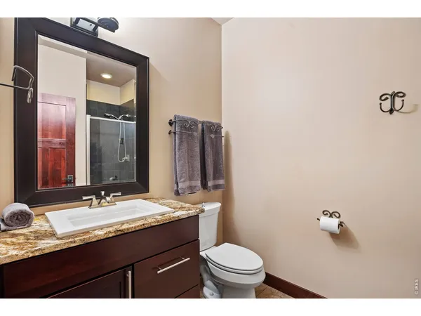 a bathroom with a granite countertop sink toilet and mirror