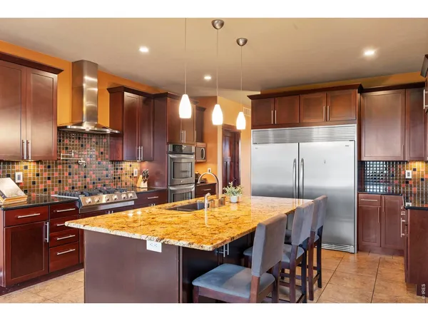 a kitchen with stainless steel appliances kitchen island granite countertop a table chairs and a refrigerator