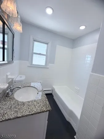 a bathroom with a granite countertop sink toilet and bathtub