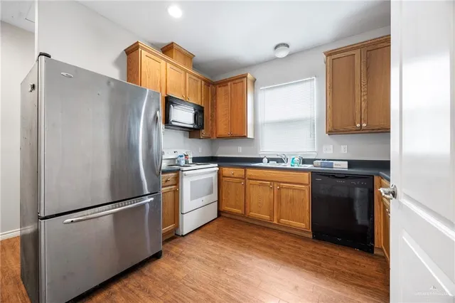 a kitchen with granite countertop a refrigerator stove top oven and sink