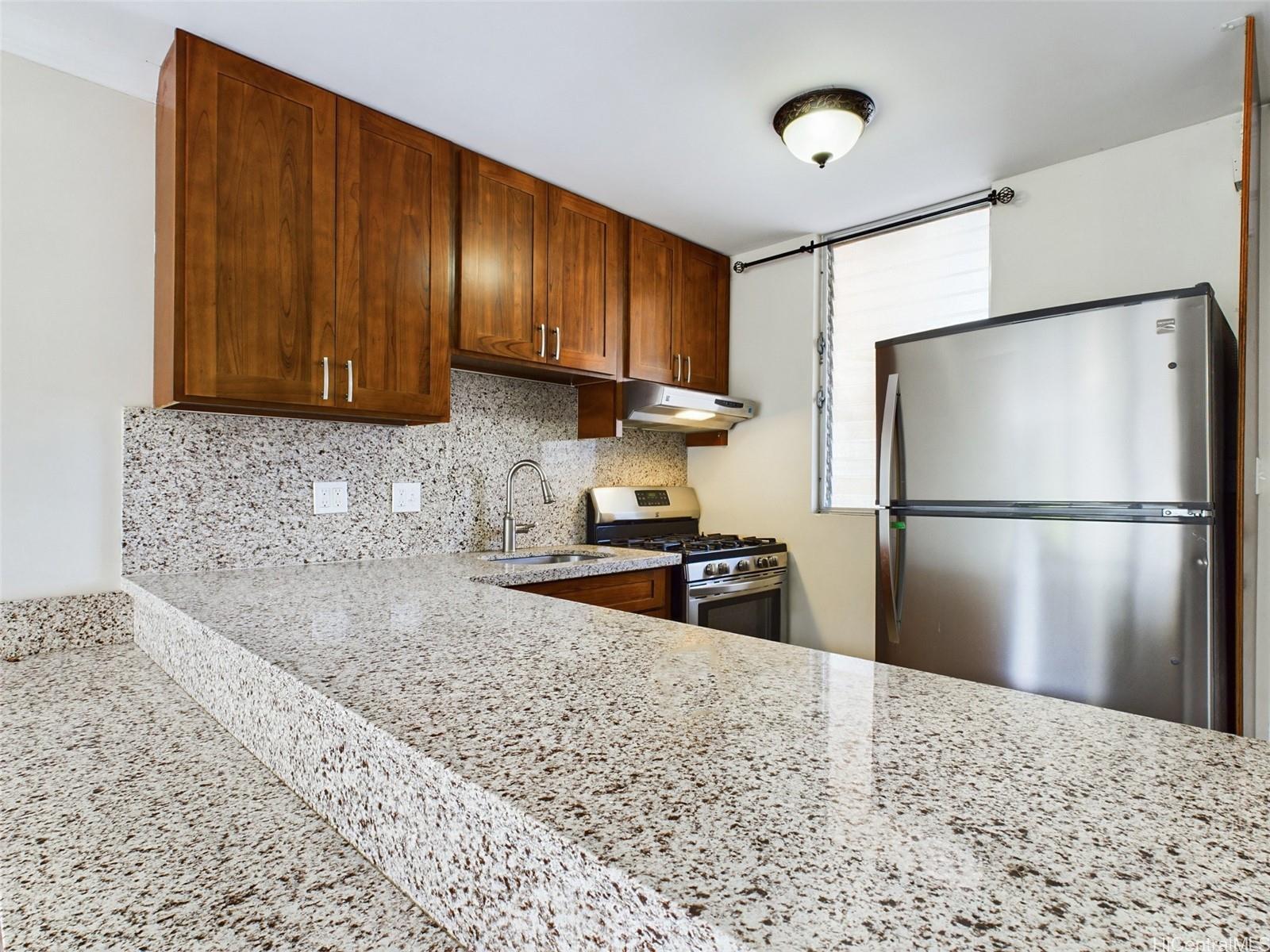 a kitchen with granite countertop wooden cabinets a refrigerator and a sink
