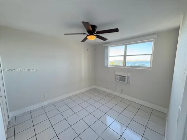 an empty room with chandelier fan and windows