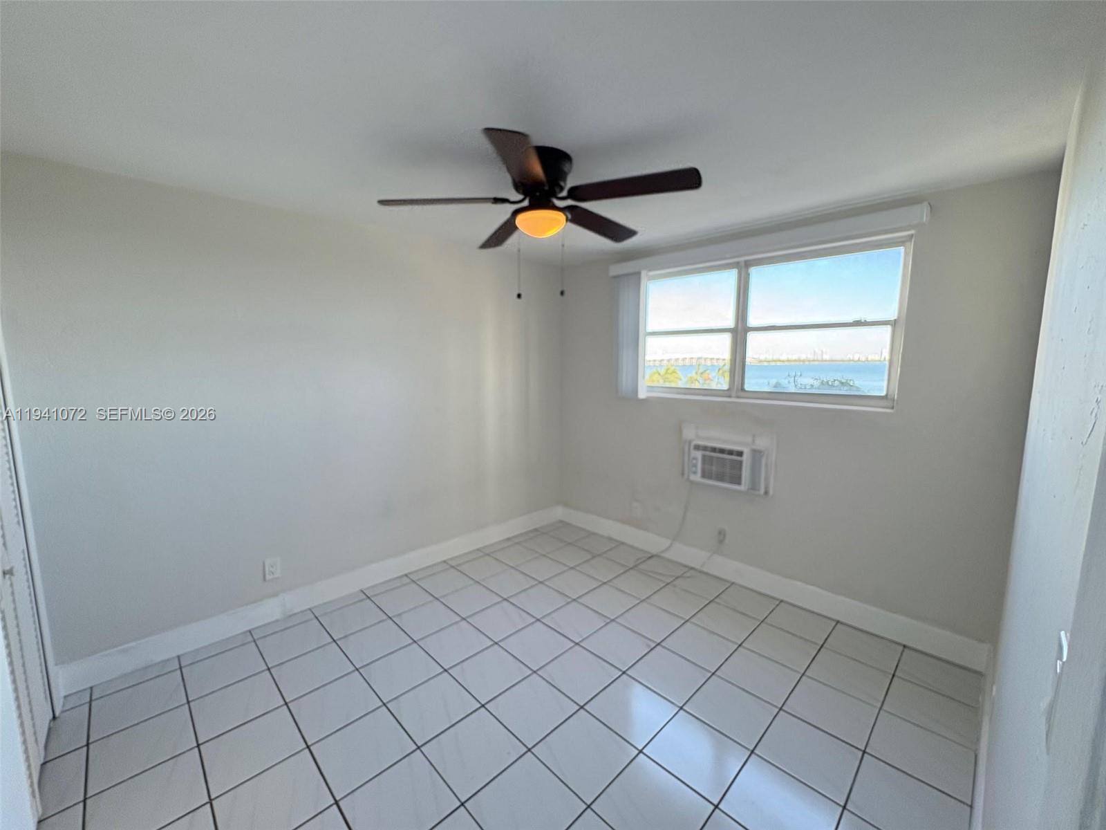 505 Northeast 30th Street, Unit 506 Miami, FL 33137 - Photo 10 of 26 an empty room with chandelier fan and windows
