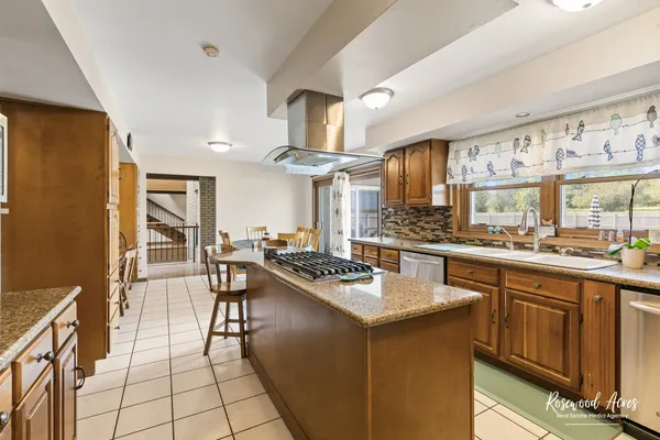 a kitchen with stainless steel appliances granite countertop a stove a sink dishwasher a refrigerator a oven and couches with wooden floor