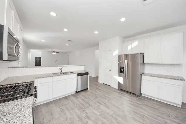 a view of a kitchen with refrigerator and white cabinets
