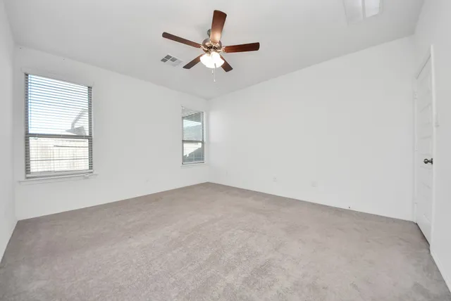 an empty room with a ceiling fan and a window