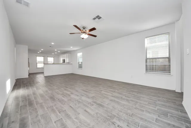a view of empty room with wooden floor and fan
