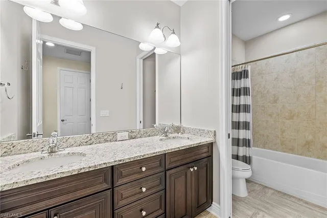 a bathroom with a granite countertop sink a toilet a mirror and shower