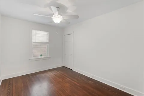 an empty room with wooden floor fan and windows