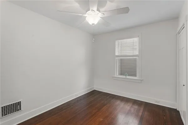 an empty room with wooden floor and a ceiling fan