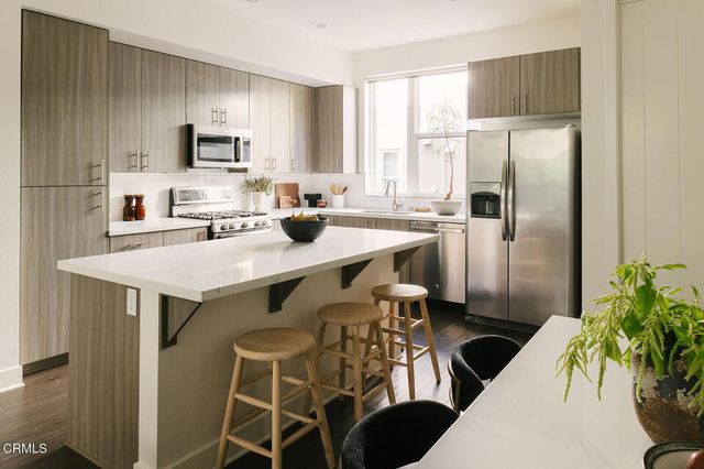 a kitchen with stainless steel appliances a table chairs refrigerator and microwave