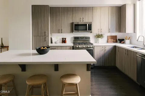 a kitchen with a sink a stove cabinets and chairs