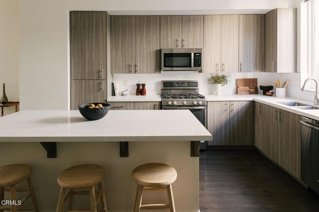 a kitchen with a sink a stove cabinets and chairs