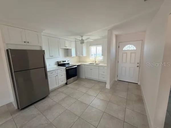 a kitchen with a refrigerator a stove top oven and cabinets