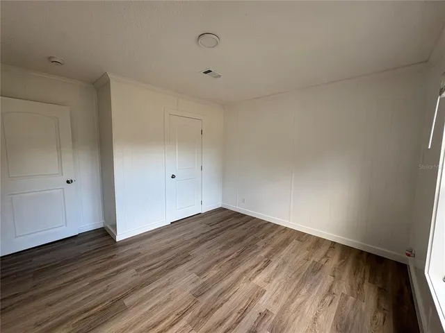 a view of a room with wooden floor mirror and windows