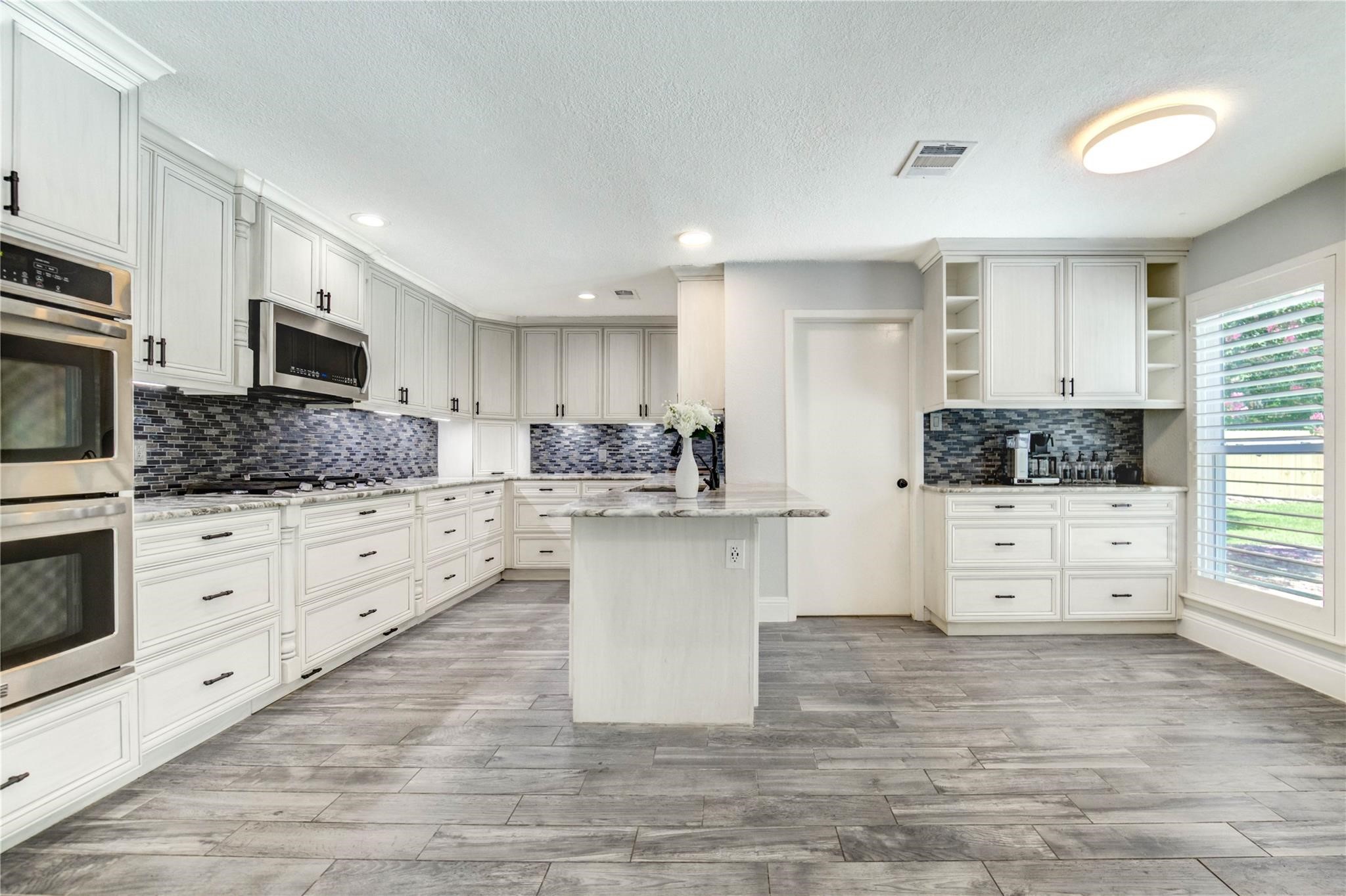 1904 Nursery Road The Woodlands, TX 77380 - Photo 15 of 43 a kitchen with stainless steel appliances kitchen island granite countertop a stove a sink and white cabinets