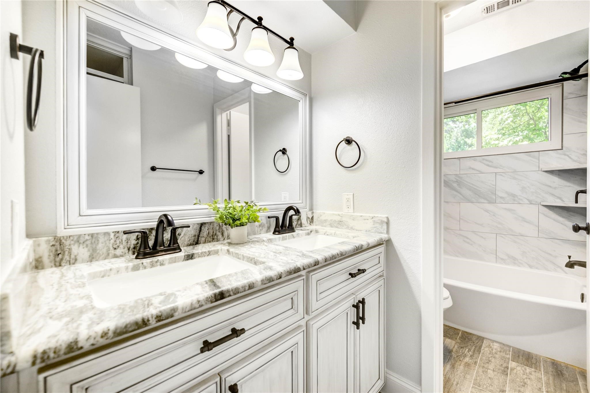 1904 Nursery Road The Woodlands, TX 77380 - Photo 25 of 43 a bathroom with a granite countertop sink a mirror and a bathtub