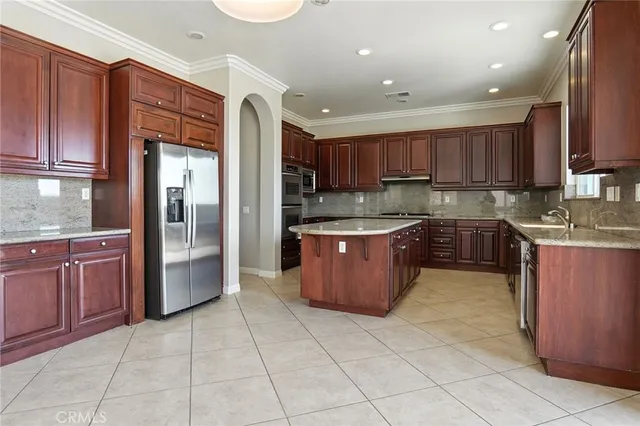 a kitchen with stainless steel appliances granite countertop a stove top oven a sink and a refrigerator