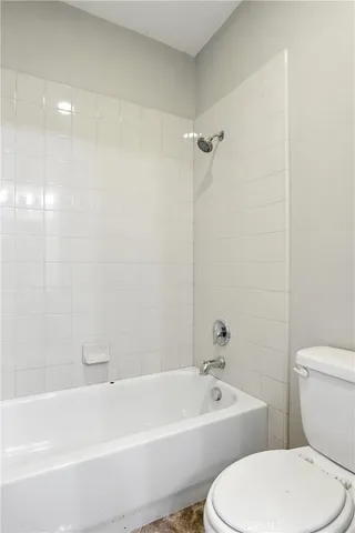 a white toilet sitting next to a bath tub