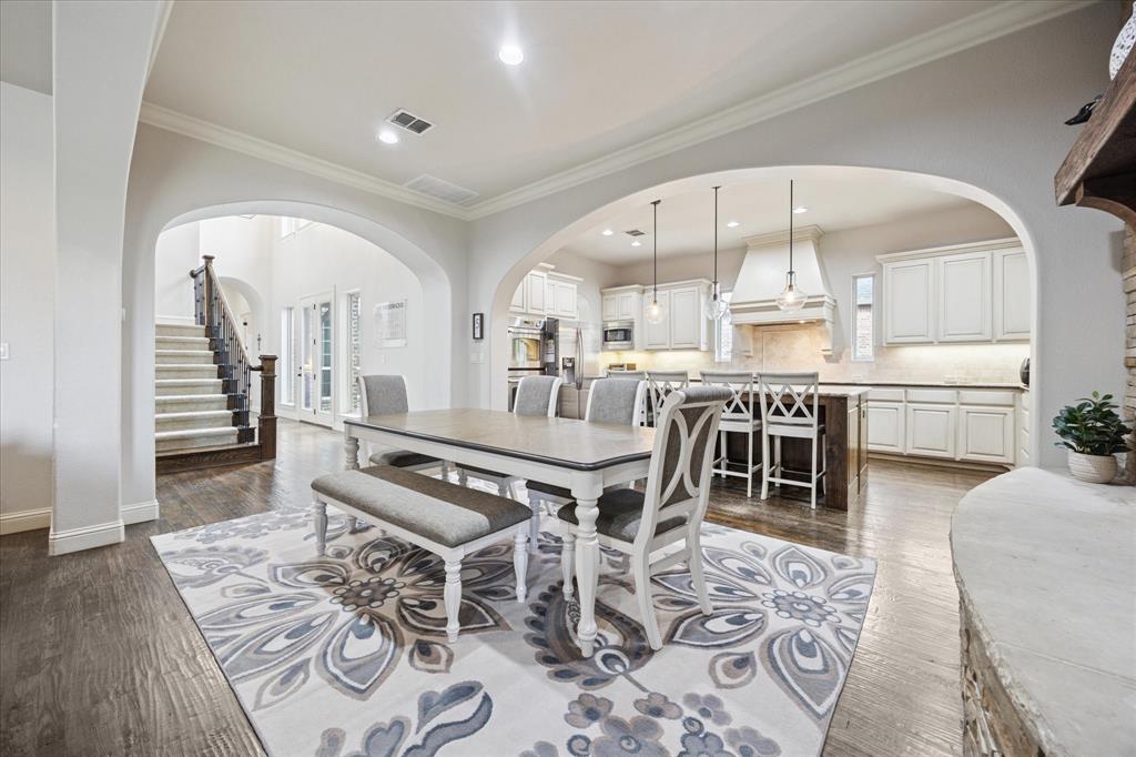 580 Butchart Drive Prosper, TX 75078 - Photo 3 of 40 Dining space with crown molding, arched walkways, dark wood-style floors, recessed lighting, and baseboards