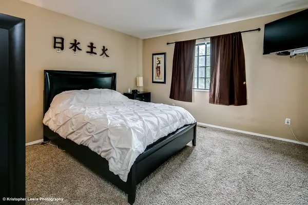 a bedroom with a bed and a flat tv screen on a dresser