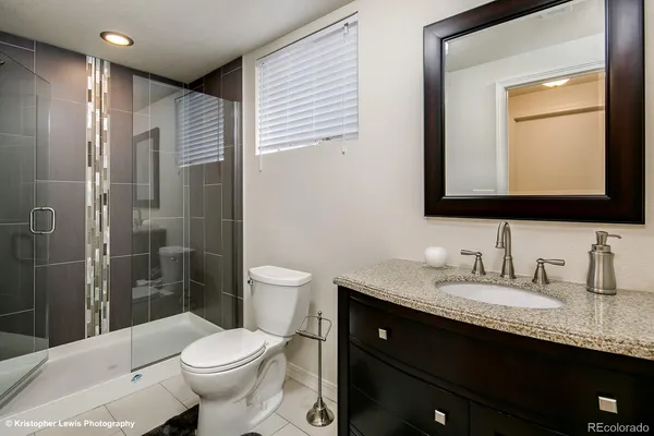 a bathroom with a granite countertop toilet sink and mirror