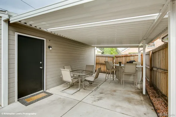 a view of a patio with table and chairs and wooden fence