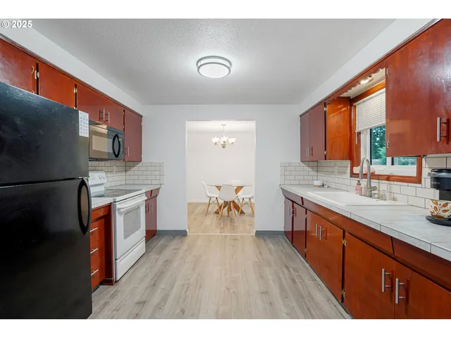 a open kitchen with stainless steel appliances granite countertop a refrigerator a sink dishwasher a stove and white countertops with wooden floor