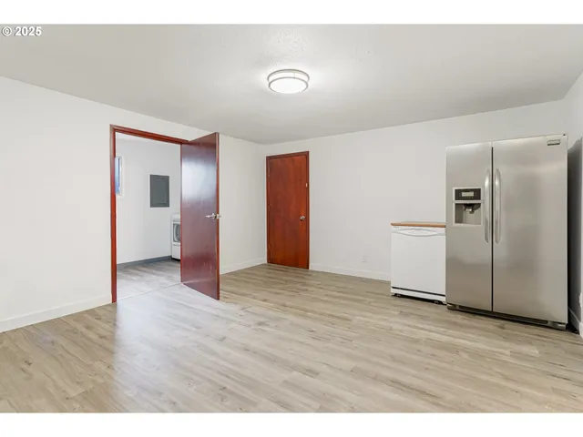 a view of an empty room with wooden floor and a cabinet