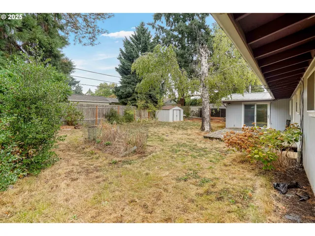 a backyard of a house with large trees and wooden fence