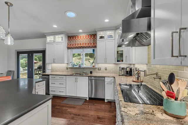 a kitchen with granite countertop a sink and white cabinets