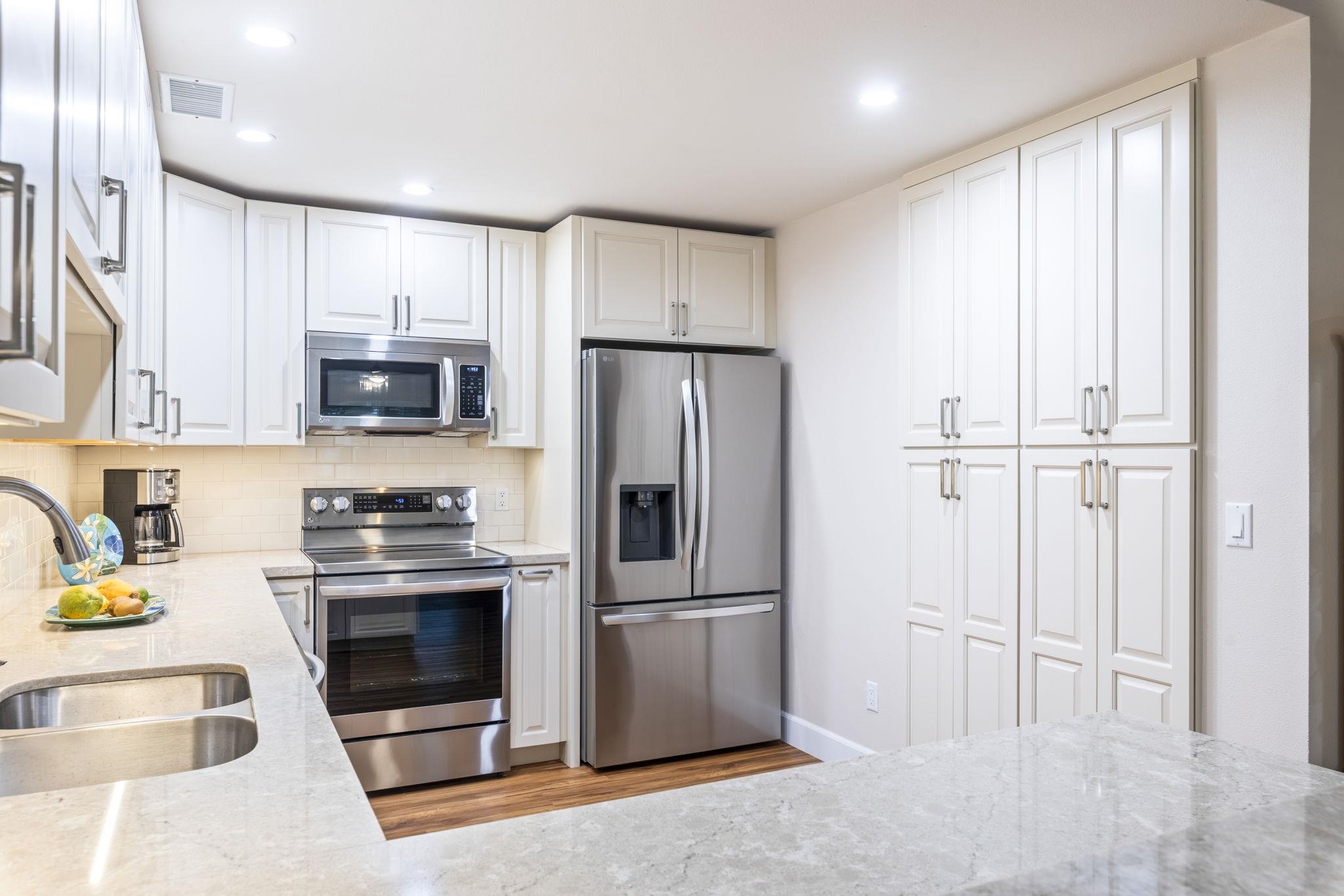 16 Kai Makani Loop, Unit D201 Kihei, HI 96753 - Photo 10 of 50 a kitchen with stainless steel appliances granite countertop a refrigerator a stove a sink and a microwave