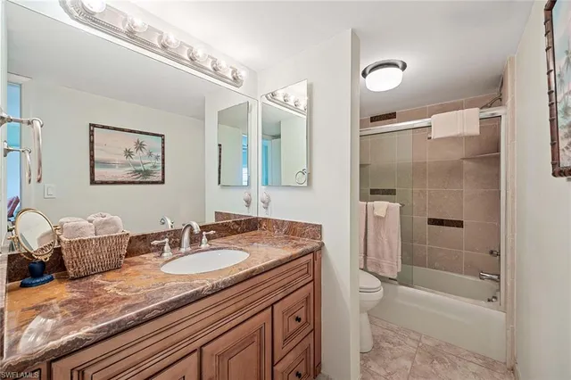 a bathroom with a granite countertop sink a toilet a mirror and shower