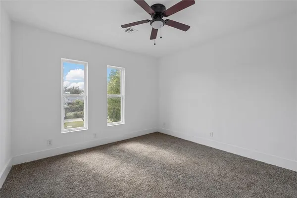 an empty room with windows and fan