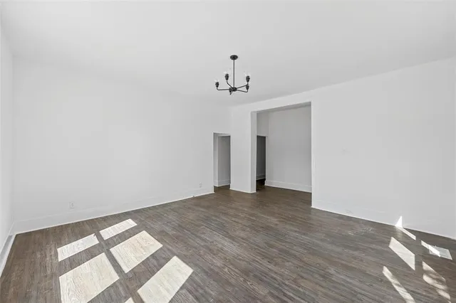 a view of an empty room with wooden floor and windows