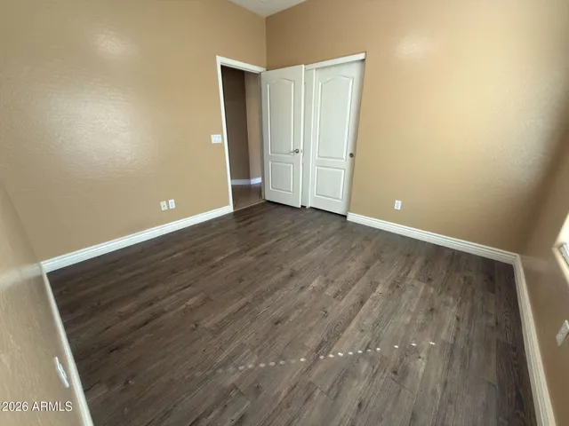 a view of an empty room with wooden floor and closet