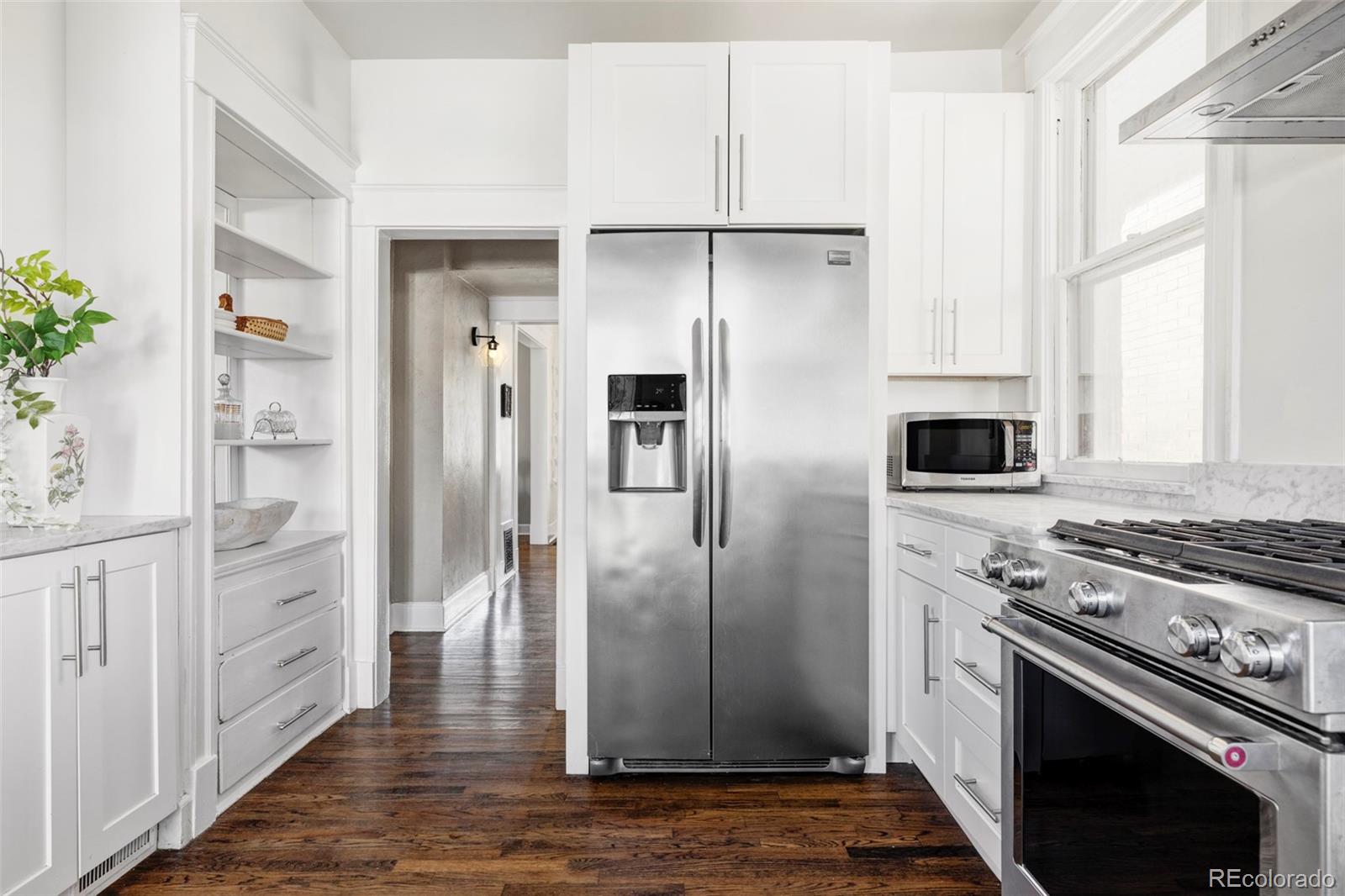 142 Logan Street Denver, CO 80203 - Photo 8 of 32 a kitchen with stainless steel appliances kitchen island granite countertop a refrigerator stove and sink