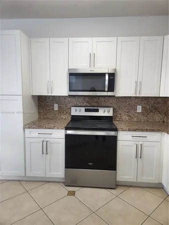 a kitchen with granite countertop white cabinets and stainless steel appliances