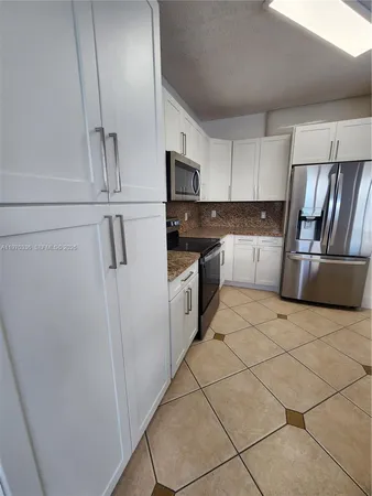 a kitchen with granite countertop a refrigerator sink and cabinets