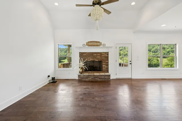 an empty room with windows fireplace and wooden floor