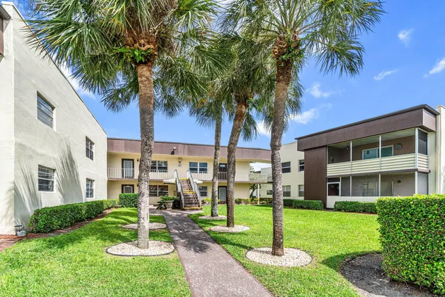 a front view of a house with a yard and palm trees