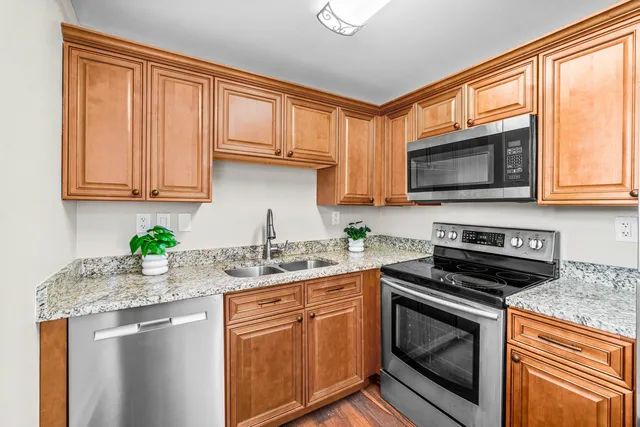 a kitchen with stainless steel appliances granite countertop a stove a sink a microwave a refrigerator and cabinets