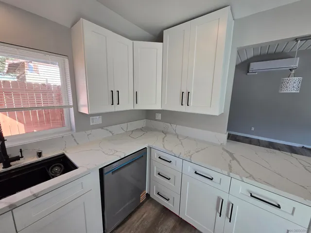 a large kitchen with kitchen island a sink dishwasher stove and white cabinets with wooden floor