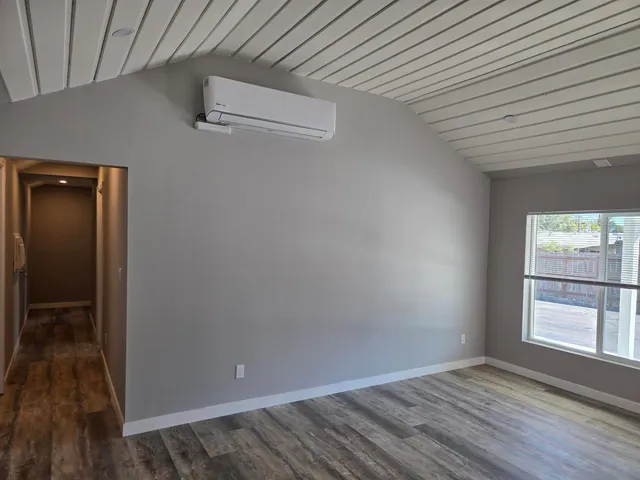 a view of an empty room with wooden floor fireplace and a window