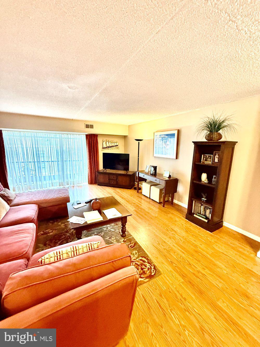 80 Welsh Tract Road, Unit G306 Newark, DE 19713 - Photo 3 of 11 a living room with furniture a flat screen tv and a floor to ceiling window