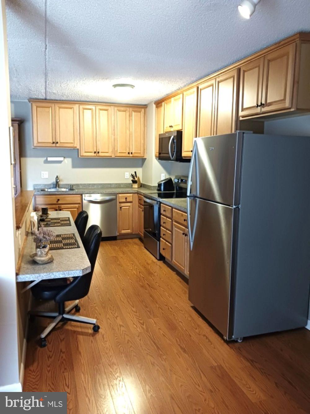 80 Welsh Tract Road, Unit G306 Newark, DE 19713 - Photo 4 of 11 a kitchen with stainless steel appliances granite countertop a refrigerator a sink dishwasher a stove and white countertops with wooden floor