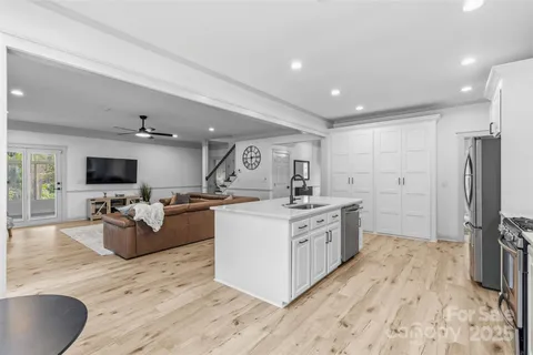 a large white kitchen with a large window a sink and stainless steel appliances